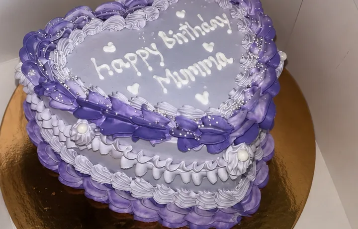 A purple heart-shaped custom cake reading Happy Birthday Mumma